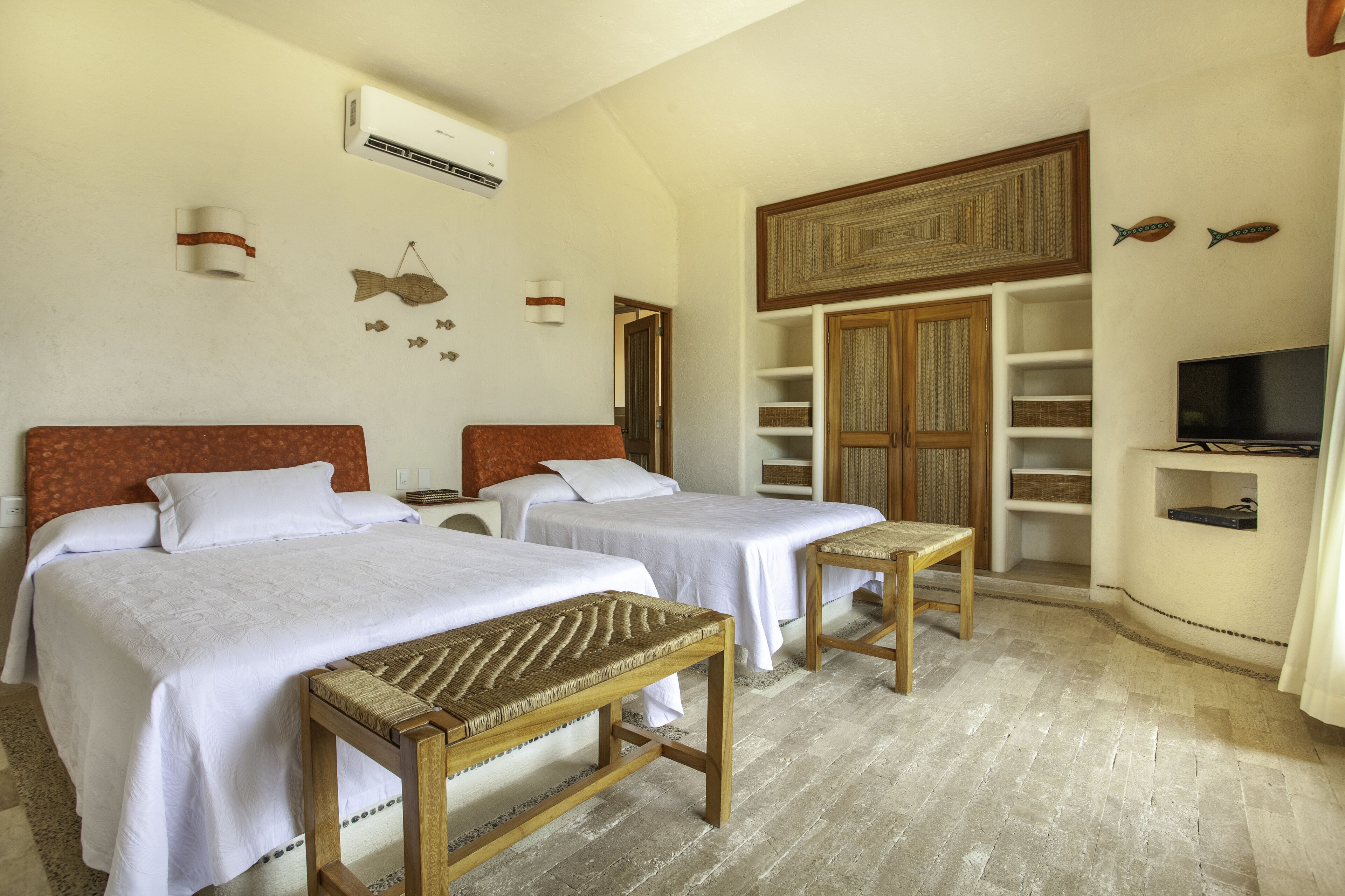 A hotel room with two beds, a TV, a wardrobe, and a small table.