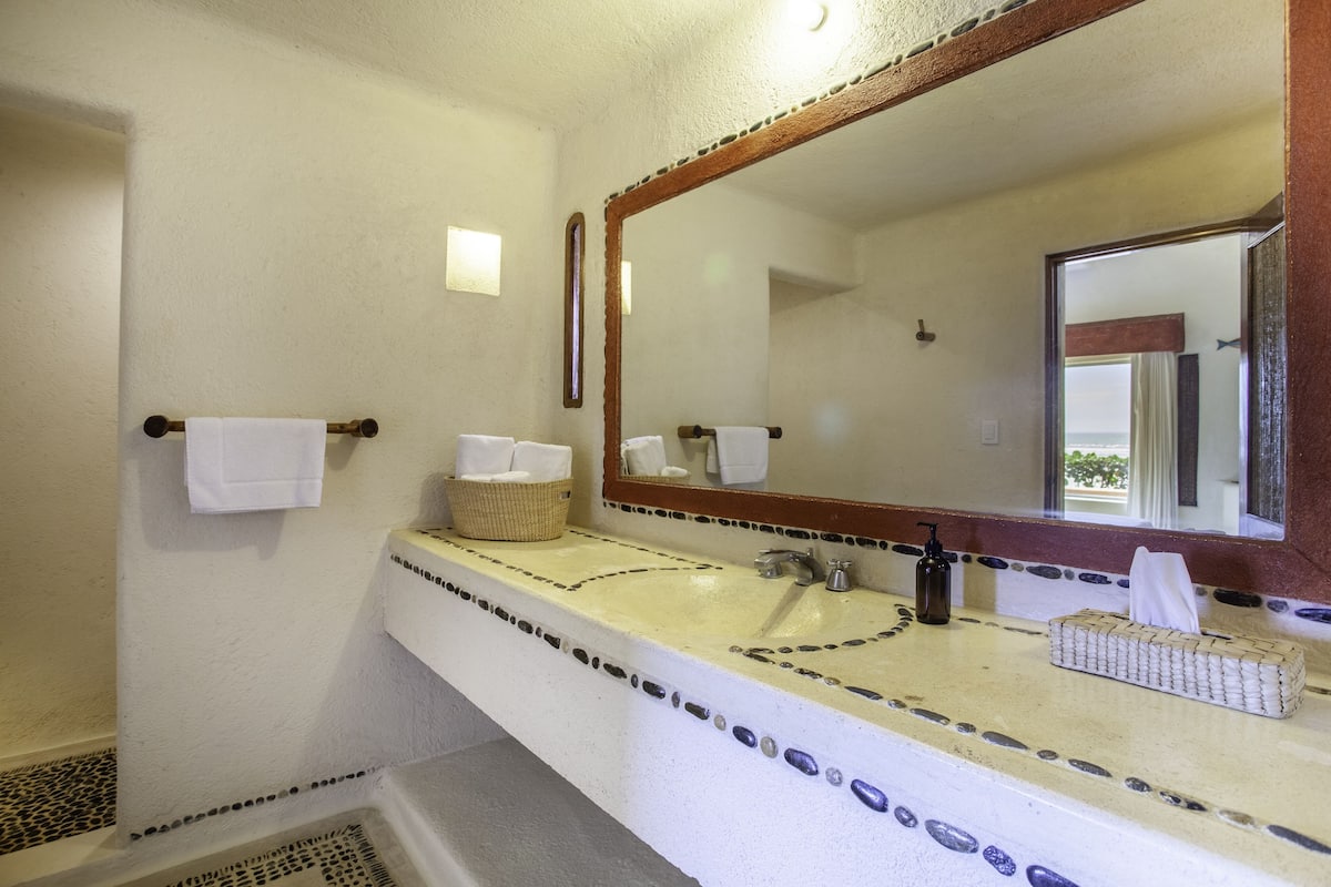Un baño con un lavamanos blanco, un espejo y un toallero.