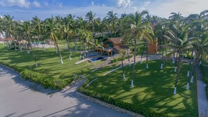 Un resort con piscina, palmeras y un césped bien cuidado.