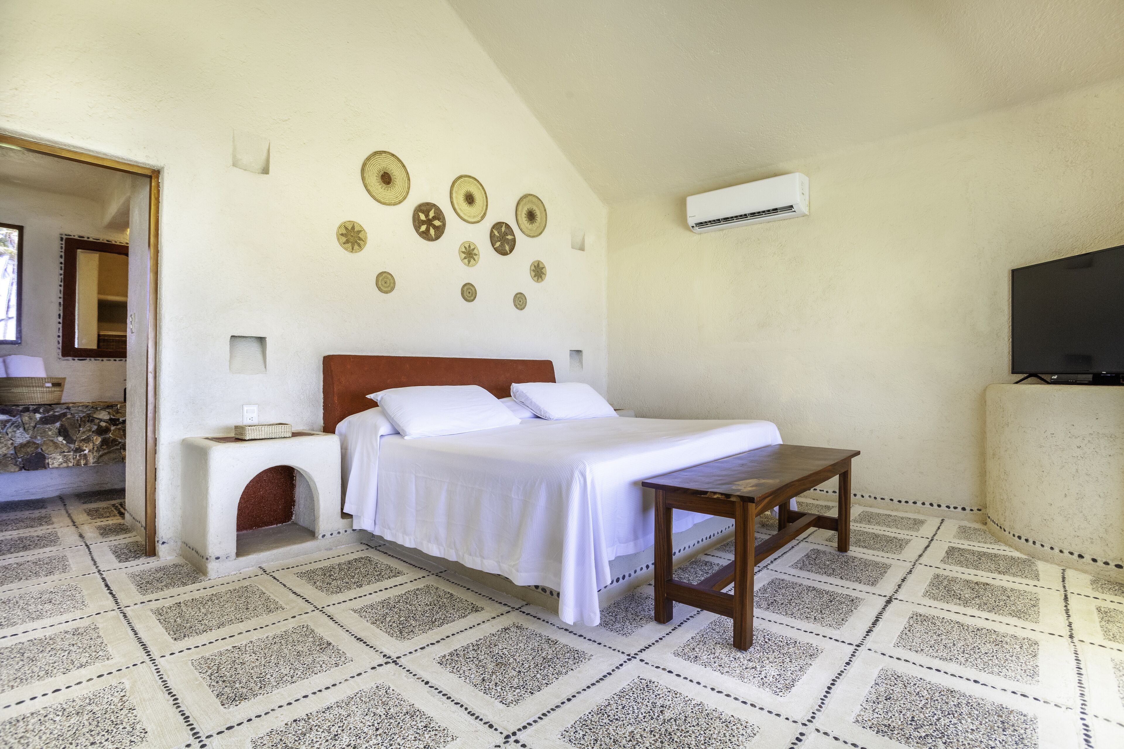 A bedroom with a bed, a nightstand, a wooden table, a TV, and decorative wall art.