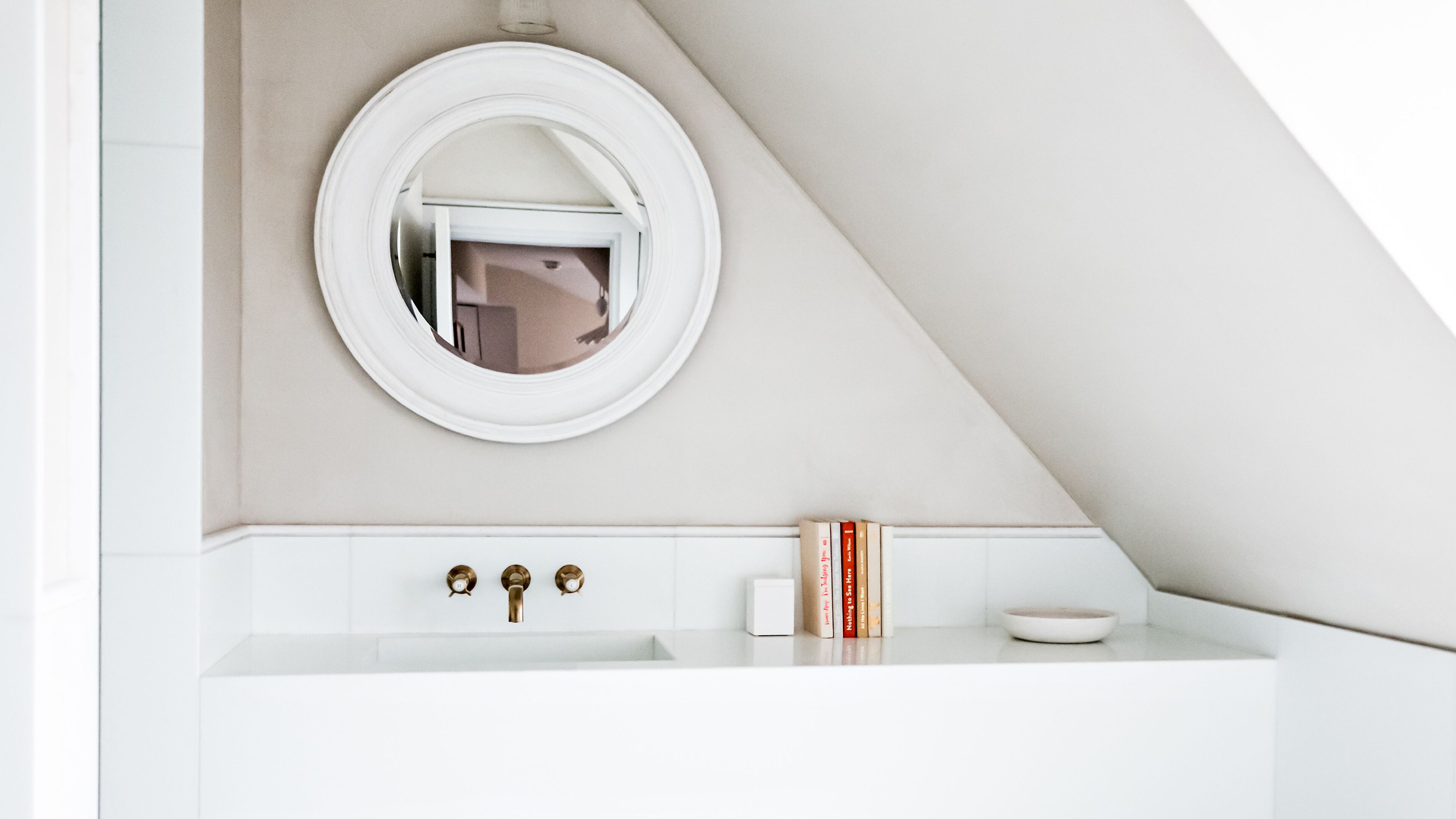 A bathroom with a white vanity, a round mirror, and a towel rack.