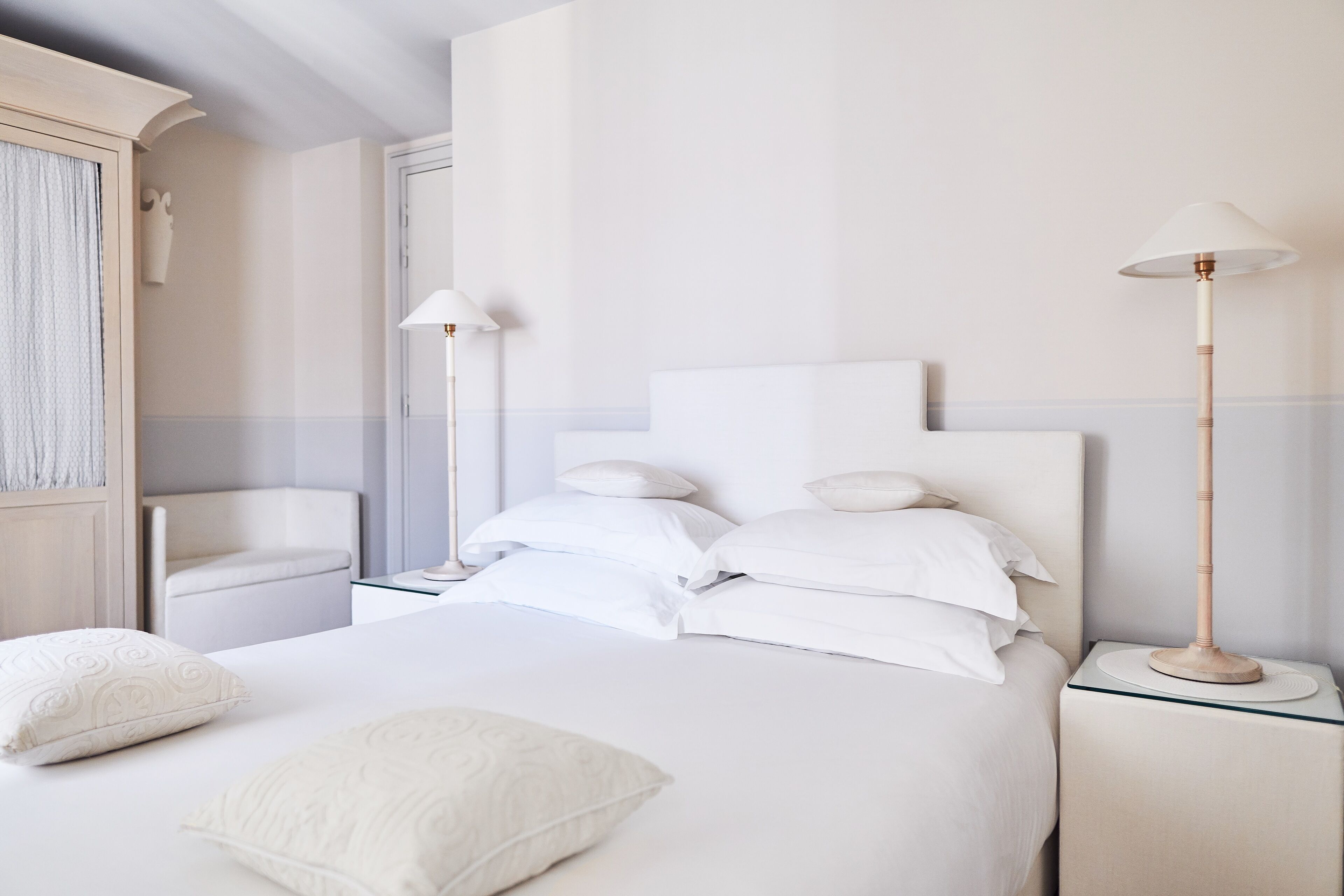 Une chambre d’hôtel au design minimaliste, avec un grand lit, deux tables de chevet et une petite table d’appoint.