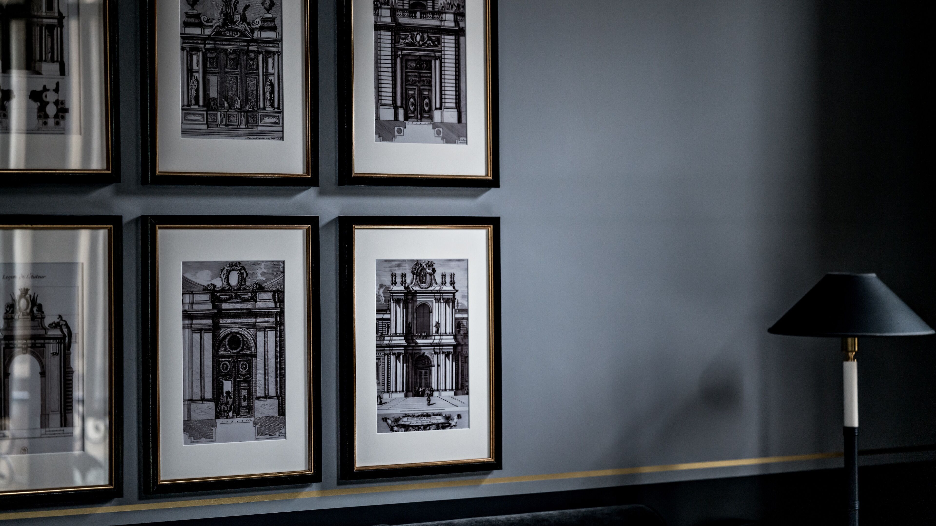 A wall with six framed black and white architectural drawings.
