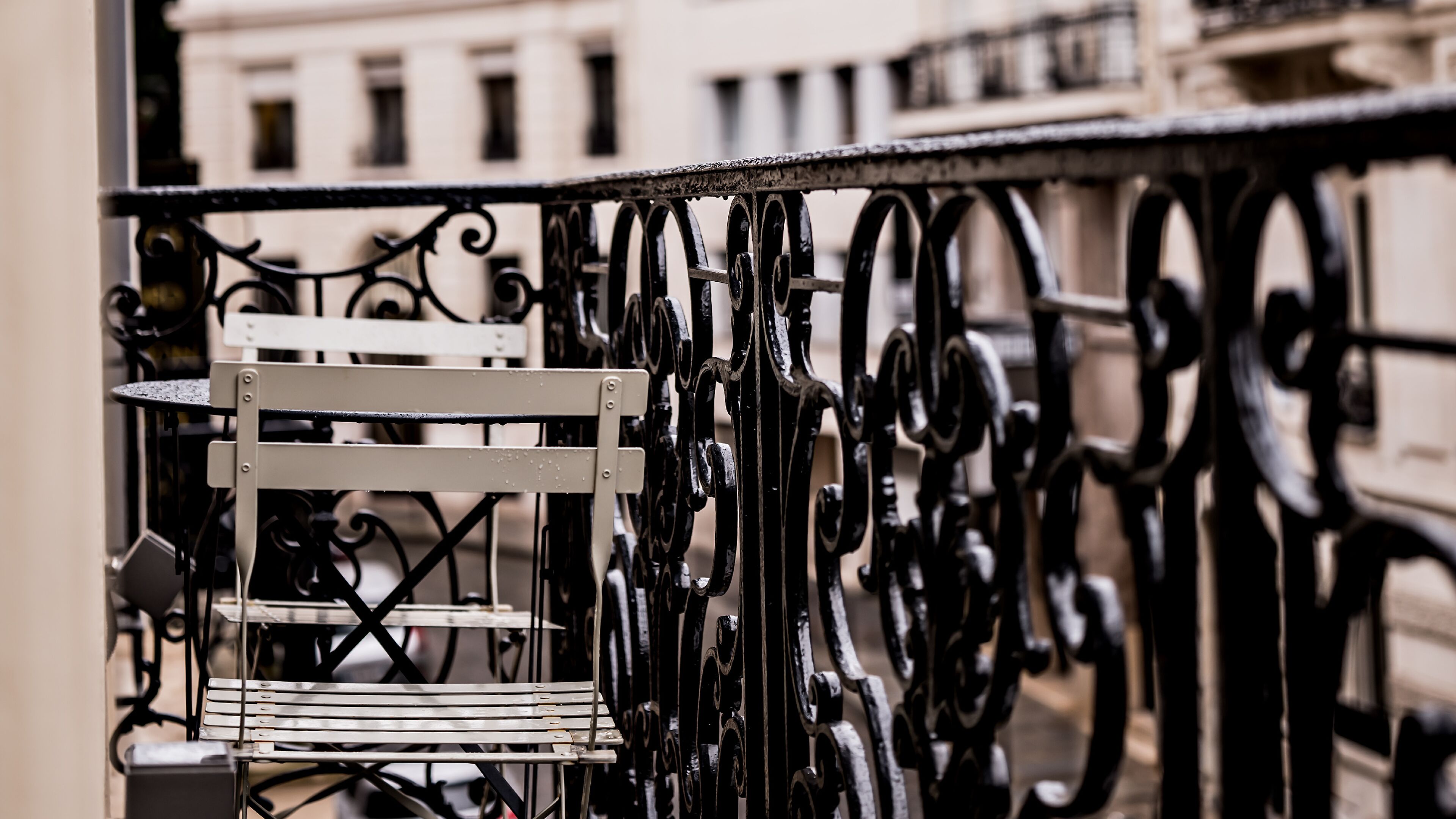A metal balcony railing with a white chair.