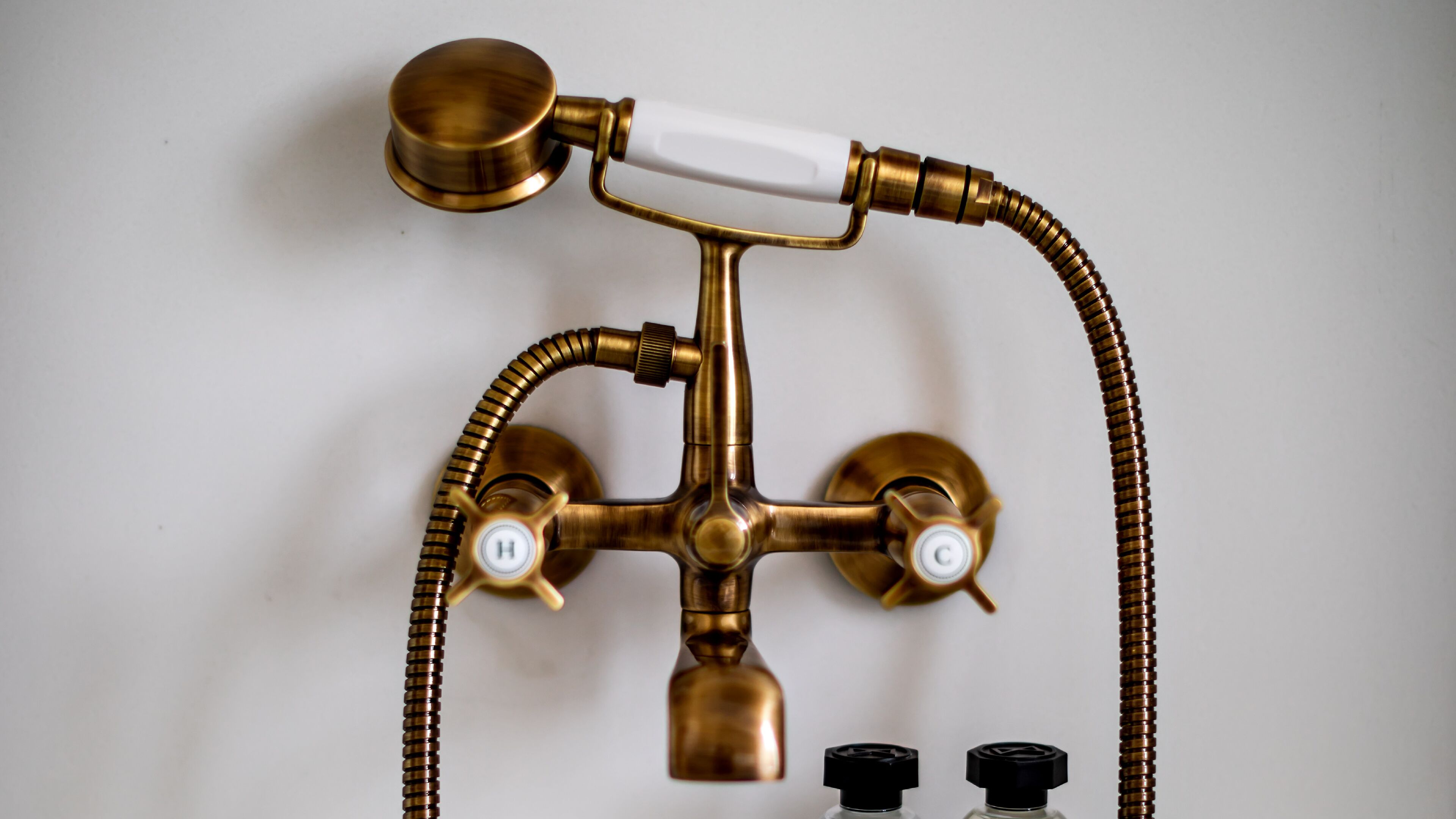 A brass bathroom fixture with two spouts and a flexible hose.