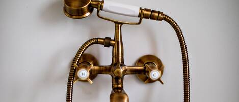 A brass bathroom fixture with two spouts and a flexible hose.