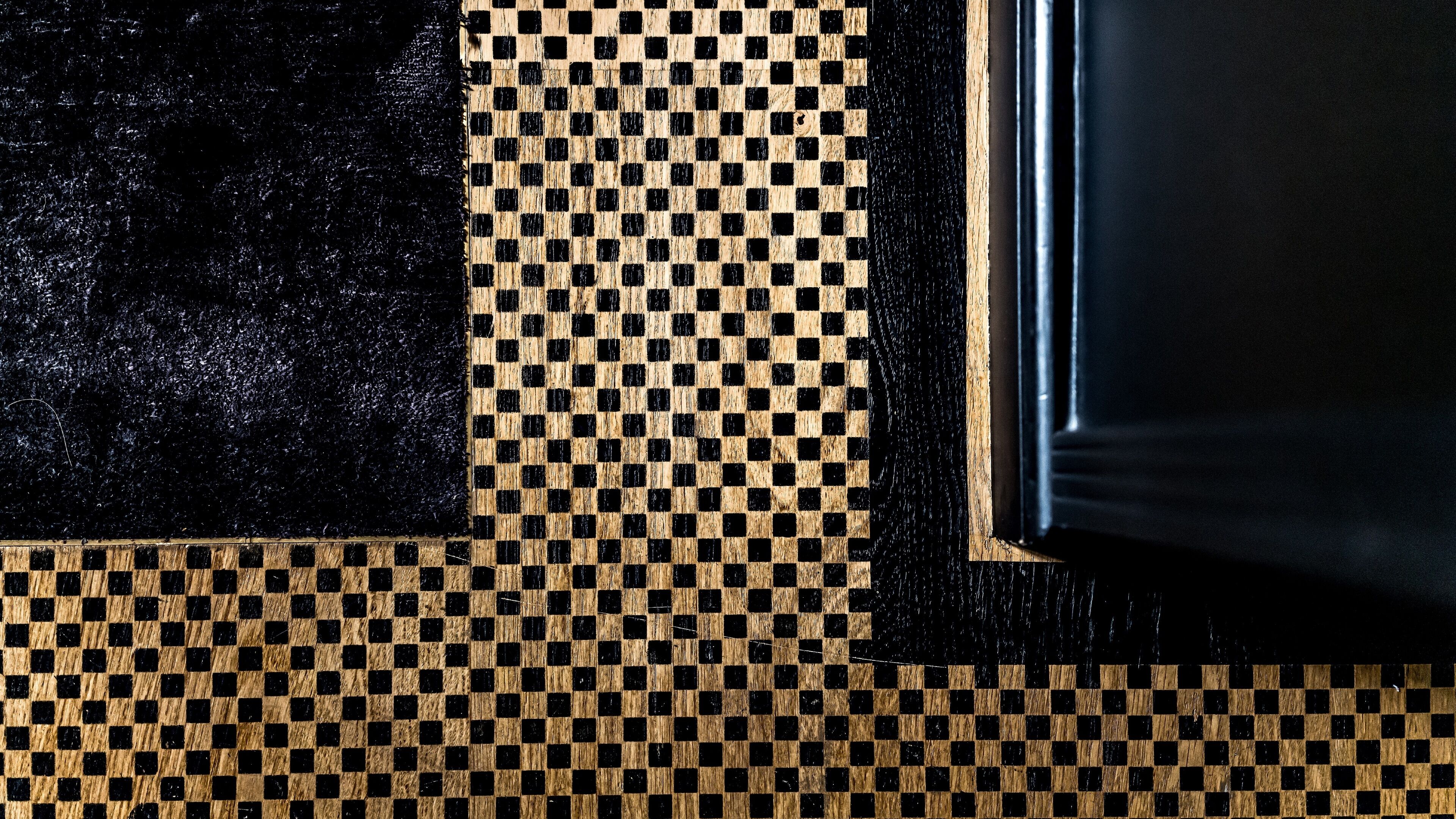A close-up of a checkered floor pattern with a black border and a wooden frame.