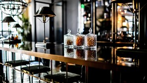 Una zona de bar con un expositor de vidrio, taburetes y luces colgantes.