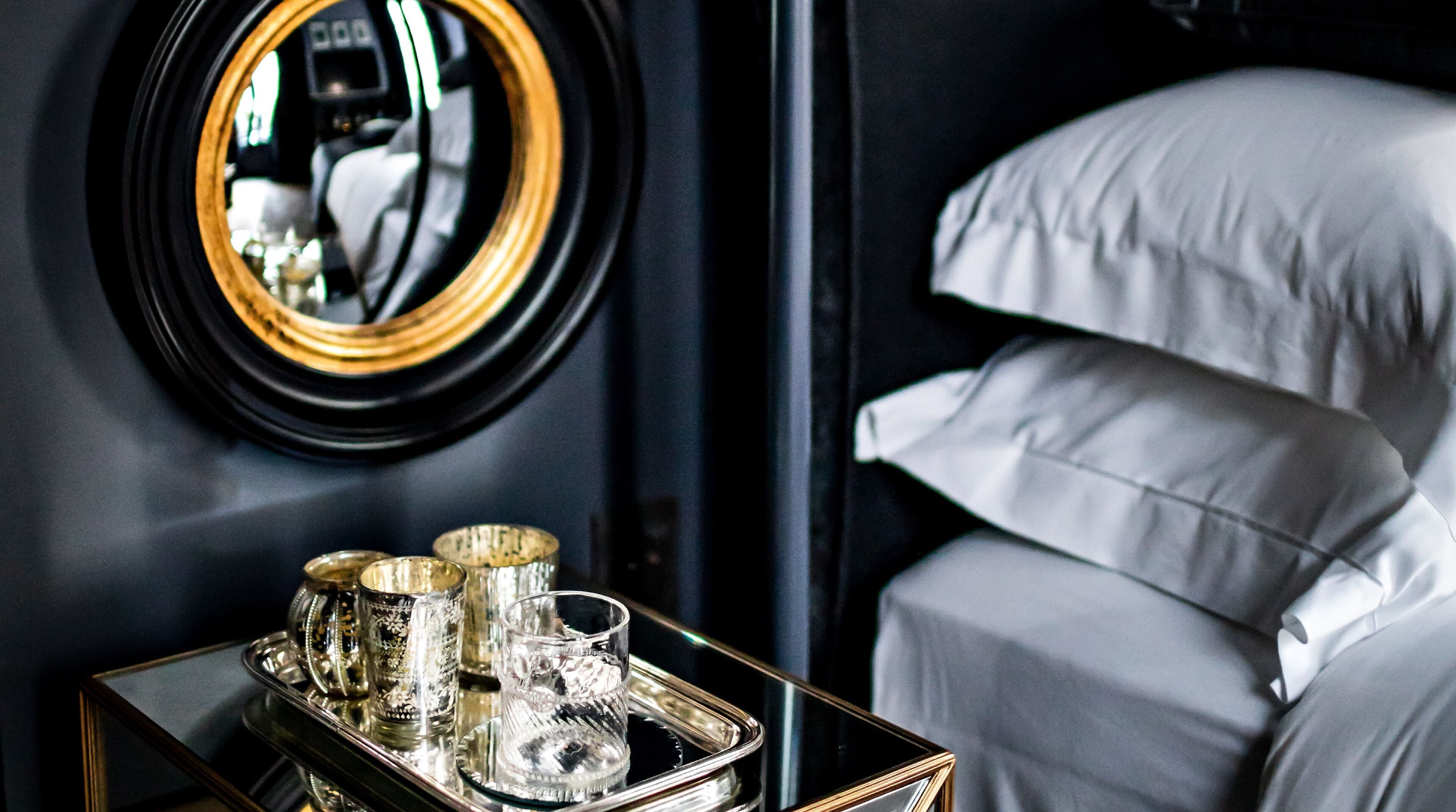 Una habitación con una cama, un espejo y una bandeja con vasos.