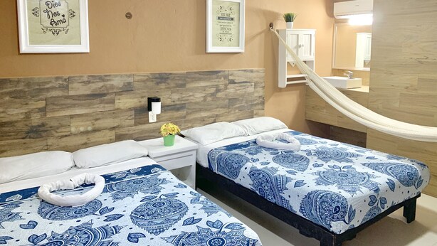 A hotel room with two beds, a hammock, and two framed motivational posters on the wall. - Hotel DNA Cancun (Cancun)