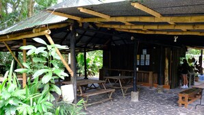 An outdoor covered area with stone flooring, wooden benches, and a rustic shelter. - Costa Rica Glamping (La Virgen)