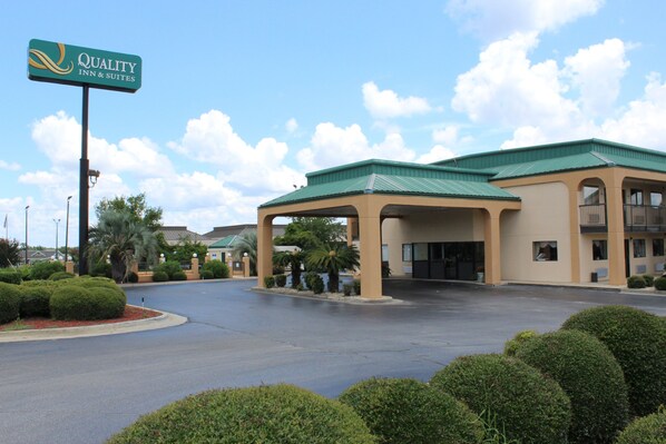 A hotel with a green roof, a covered entrance, and a sign reading "Quality Inn & Suites".