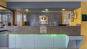 A hotel reception desk with a 'Quality by Choice Hotels' sign, a glass partition, and a check-in counter. - Quality Inn & Suites Dublin (Dublin)