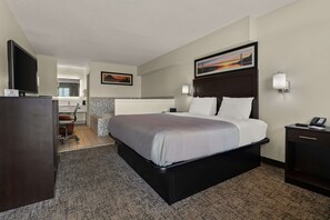 A hotel room with a large bed, a desk with a chair, a TV, and a painting on the wall. - Quality Inn & Suites Dublin (Dublin)