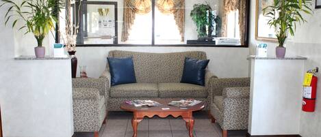 A living room with a sofa, two armchairs, a coffee table, and two potted plants.