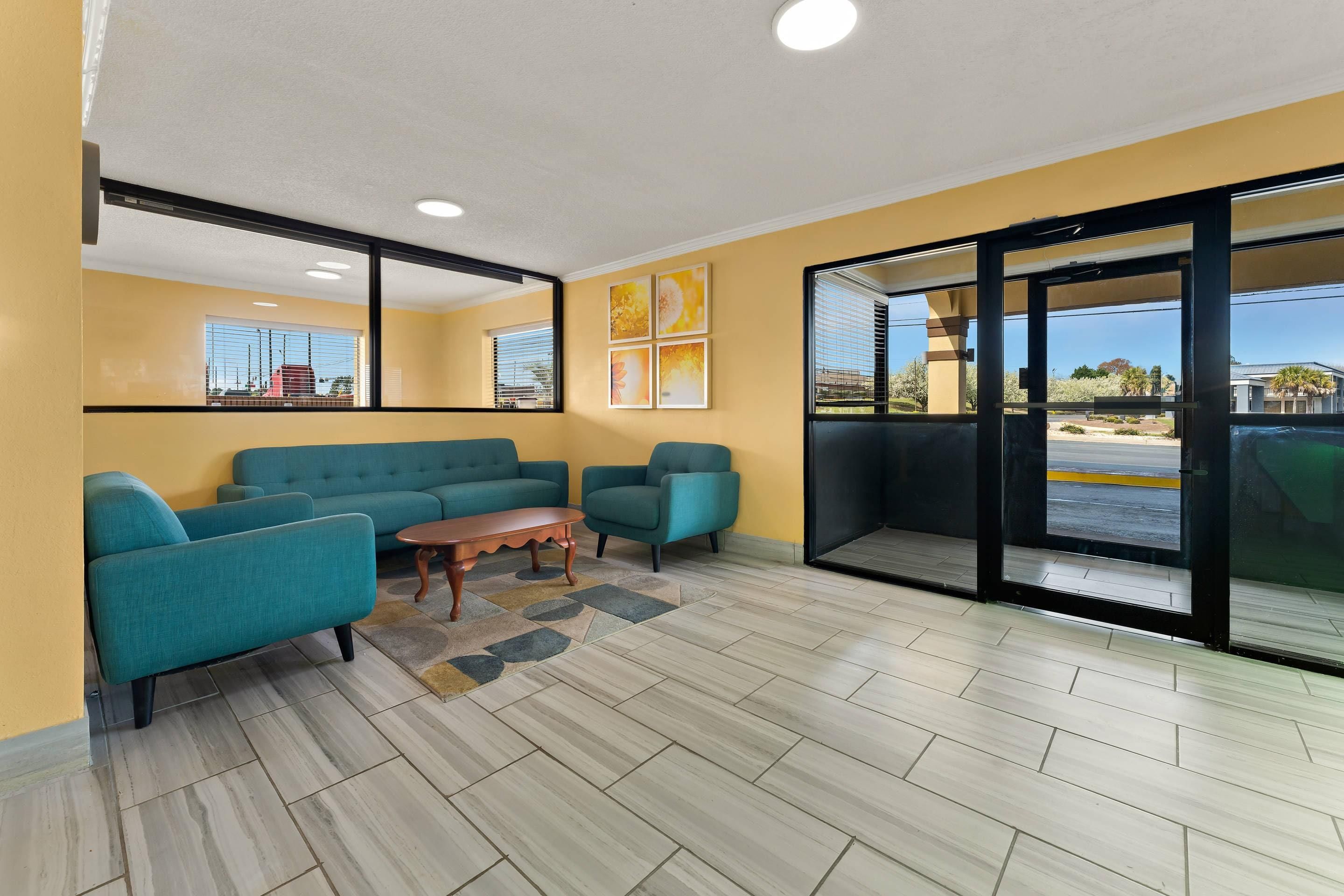 A room with a sofa set, a coffee table, and a view through a glass door to the outside.