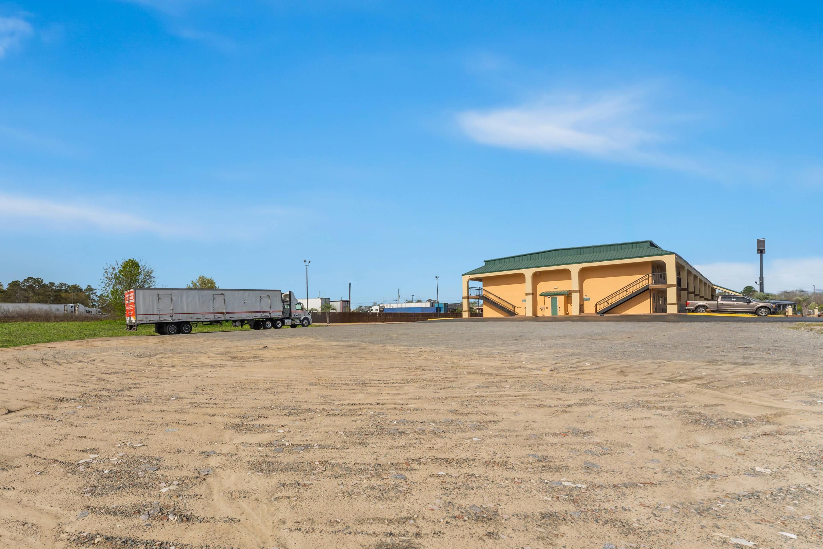An empty parking lot with a building that has a green roof and a ramp leading to the entrance.