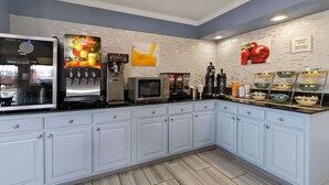 A modern kitchen with a coffee machine, microwave, and a breakfast bar with bowls. - Quality Inn & Suites Dublin (Dublin)