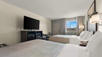 A hotel room with two beds, a television, a minibar, and a window with curtains.