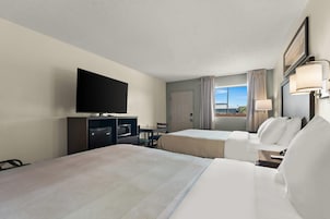 Habitación de hotel con dos camas, televisión, minibar y ventana con cortinas.
