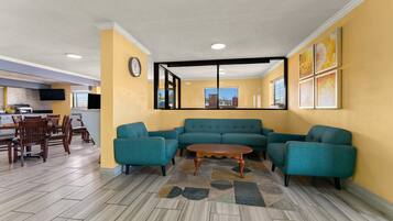 A living room with a teal sofa set, a wooden coffee table, and a dining area with a wooden table and chairs.