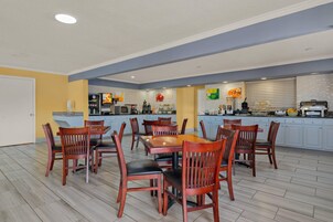 Una cocina moderna con comedor, que incluye una isla central, electrodomésticos integrados y un amplio ventanal.