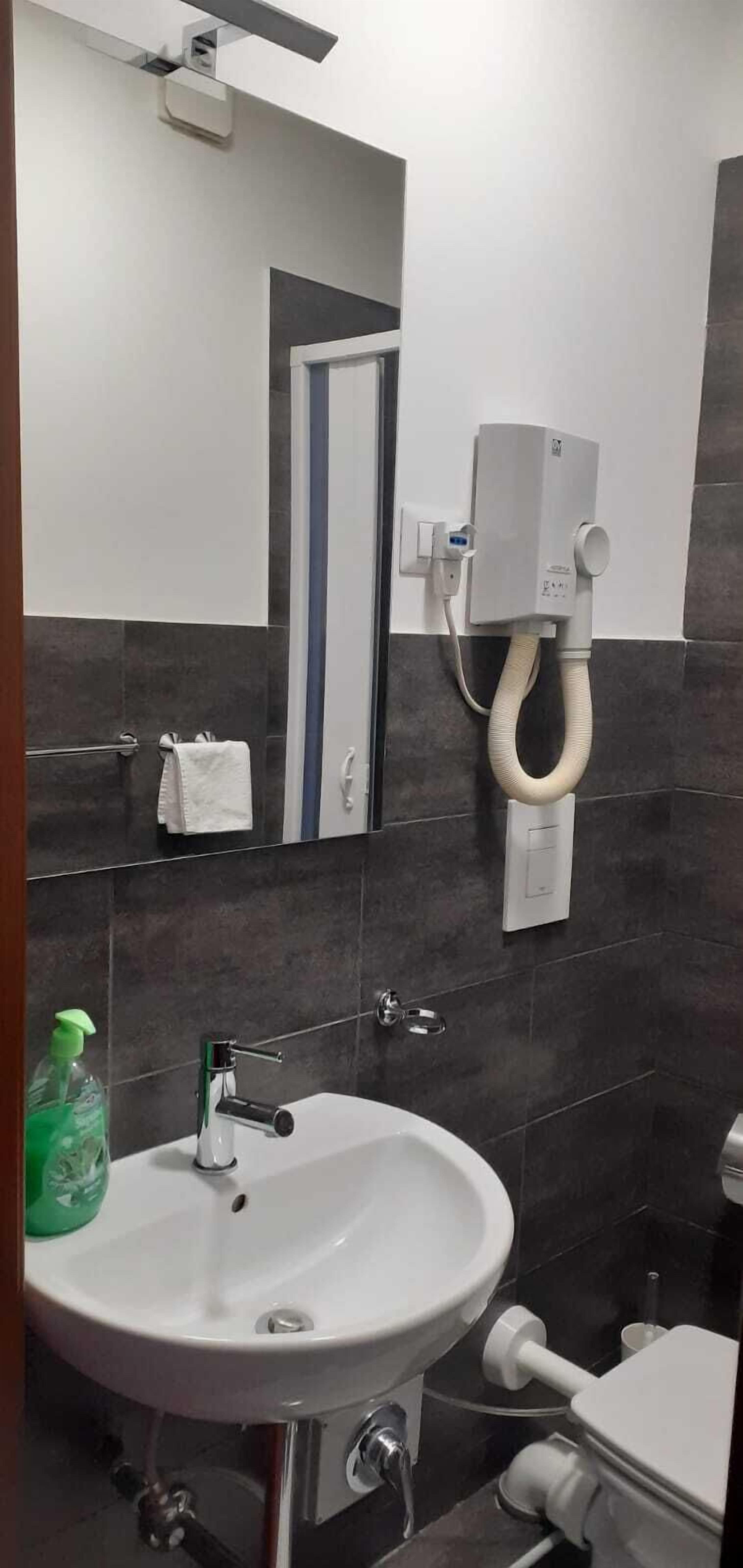 A bathroom with a white sink, a mirror, a towel rack, and a toilet.