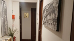 A hallway with wooden flooring, a fire extinguisher, a plant, and a framed picture of a bridge. - Domus Vatican Holidays (Rome)