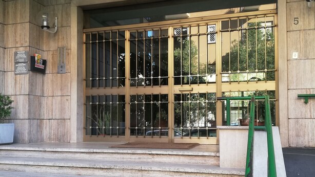 A building entrance with a set of stone steps leading up to a glass door with metal bars. - Domus Vatican Holidays (Rome)