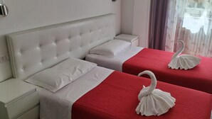 A hotel room with a white tufted headboard, two beds with red bedding, white pillows, and a decorative swan on each bed. - Domus Vatican Holidays (Rome)