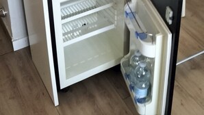 A compact kitchenette with a coffee maker, kettle, and a small refrigerator with water bottles. - Domus Vatican Holidays (Rome)