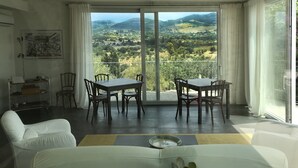A balcony with a table and chairs, a sofa, and a view of a hilly landscape. - Poggio del Gallo (Chiaramonte Gulfi)
