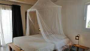 A bed with a canopy, a bedside table with a lamp, and a window with curtains. - Poggio del Gallo (Chiaramonte Gulfi)