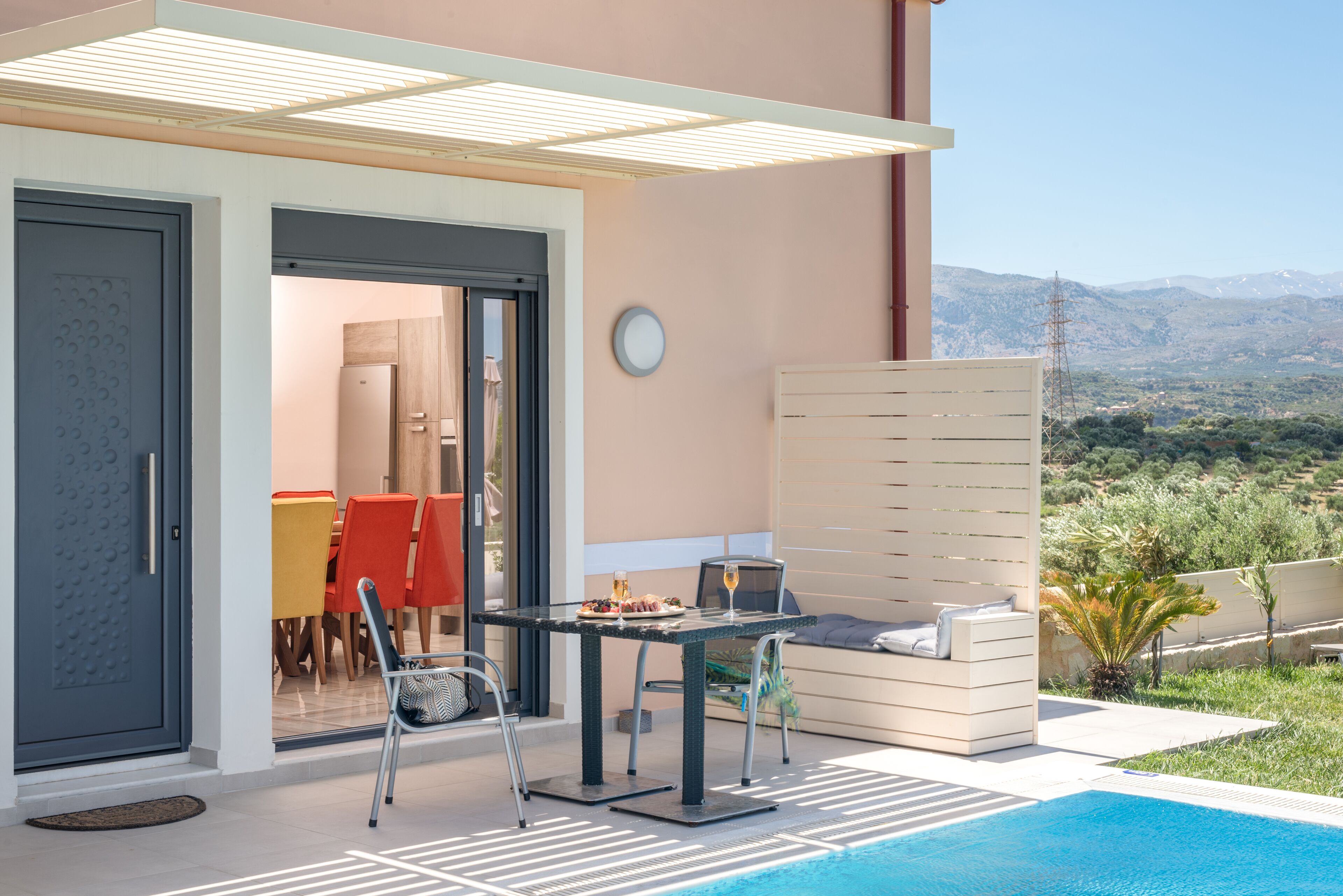 Un área de comedor al aire libre con piscina, una mesa, sillas y vistas al paisaje.