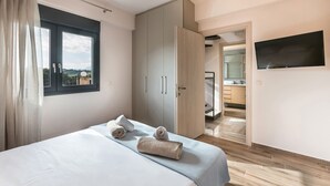 A bedroom with a bed, a wardrobe, a TV, and a bathroom visible through an open door. - Marina's Villas (Malevizi)