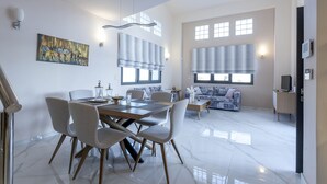 A spacious living area with a dining table, chairs, a sofa, and a television. - Marina's Villas (Malevizi)