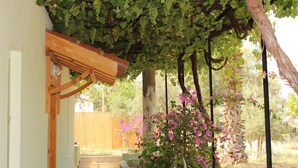 Una estructura de pérgola de madera con enredaderas y plantas florecientes debajo.