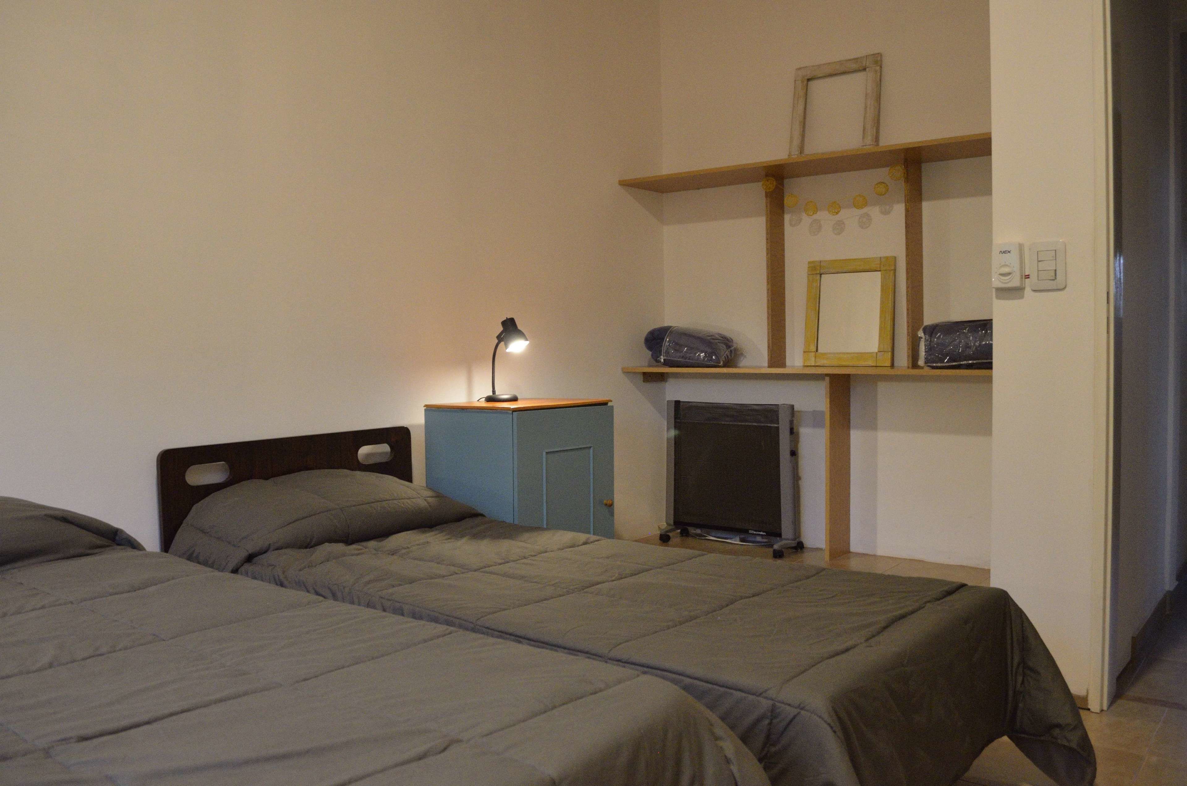 Ein Schlafzimmer mit zwei Betten, einem Schreibtisch mit Lampe und einem kleinen Fernseher.