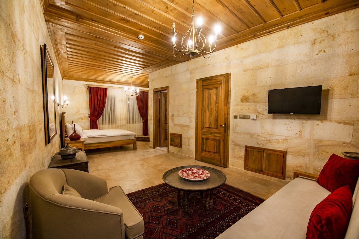 A room with a bed, a sofa, a table, and a TV mounted on the wall.