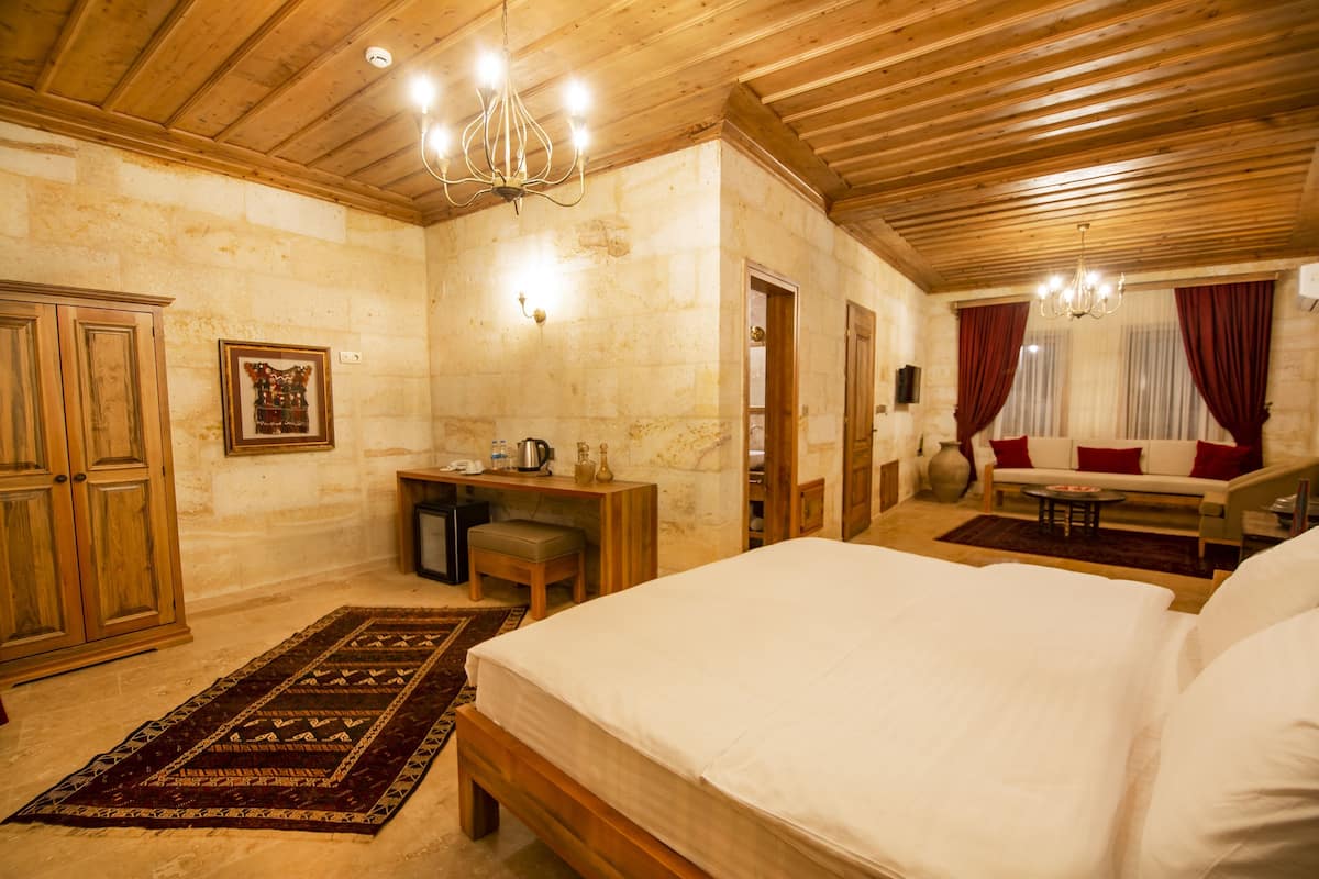 A bedroom with a wooden ceiling, a bed, a desk, a chair, and a sofa.