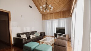 A living room with a wooden ceiling, a sofa, a coffee table, and a TV. - Casa Jainen (Ushuaia)