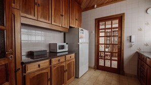 A kitchen with wooden cabinets, a microwave, and a refrigerator. - Casa Jainen (Ushuaia)