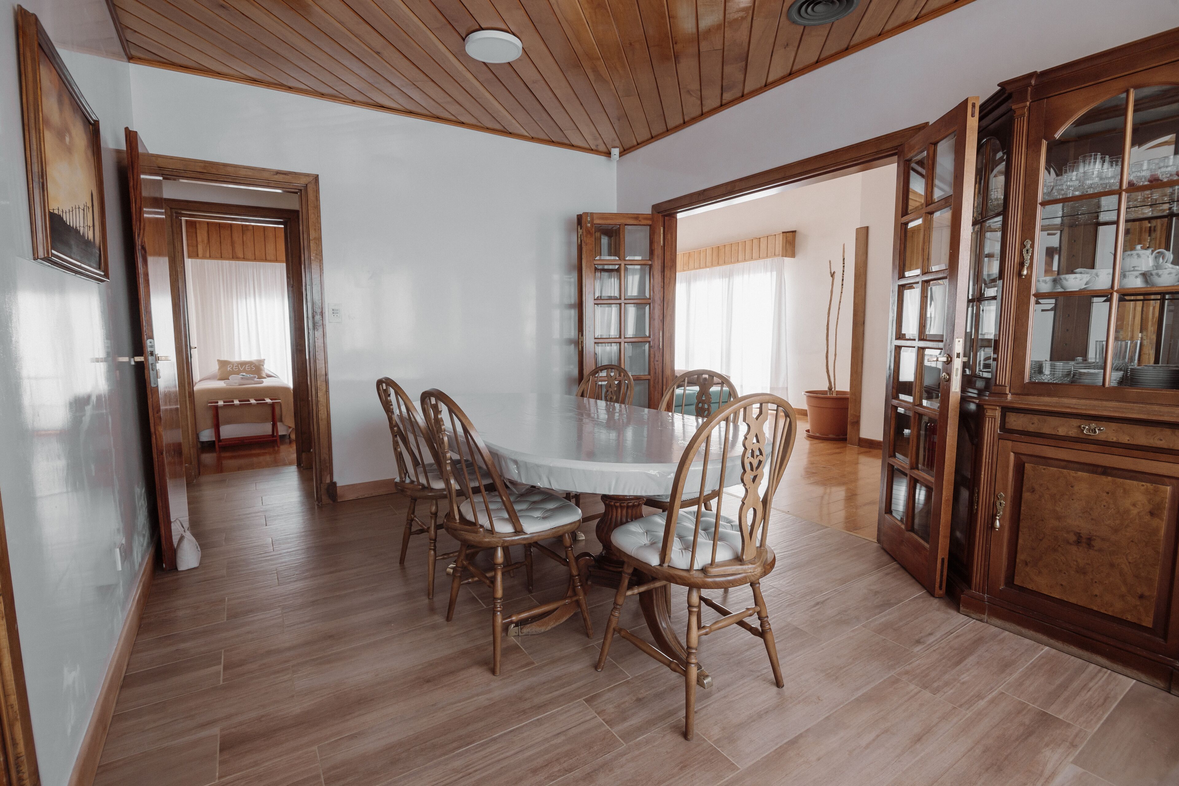 A dining area with a round table, wooden chairs, and a cabinet with glass doors.