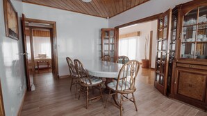 A dining area with a round table, wooden chairs, and a cabinet with glass doors. - Casa Jainen (Ushuaia)