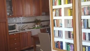 Una cocina con armarios de madera, microondas y suelo de baldosas.