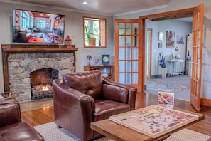 Una sala de estar con chimenea de piedra, un sillón de cuero y un televisor de pantalla plana.