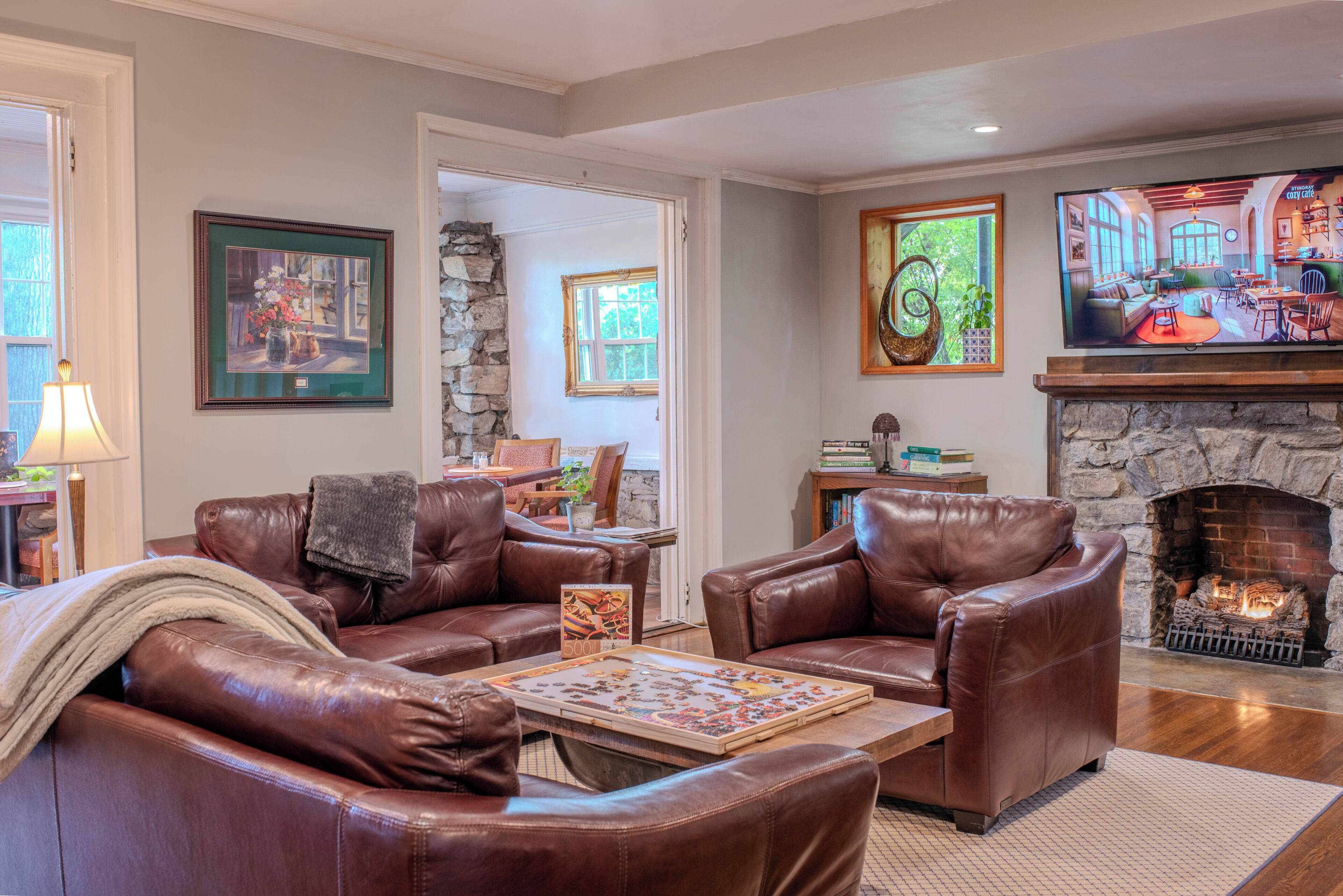 A living room with leather sofas, a fireplace, and a television.
