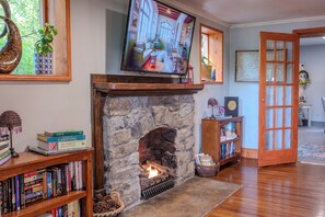 A fireplace with a stone surround, a television mounted above it, and bookshelves with books. - McKinley Edwards Inn (Bryson City)