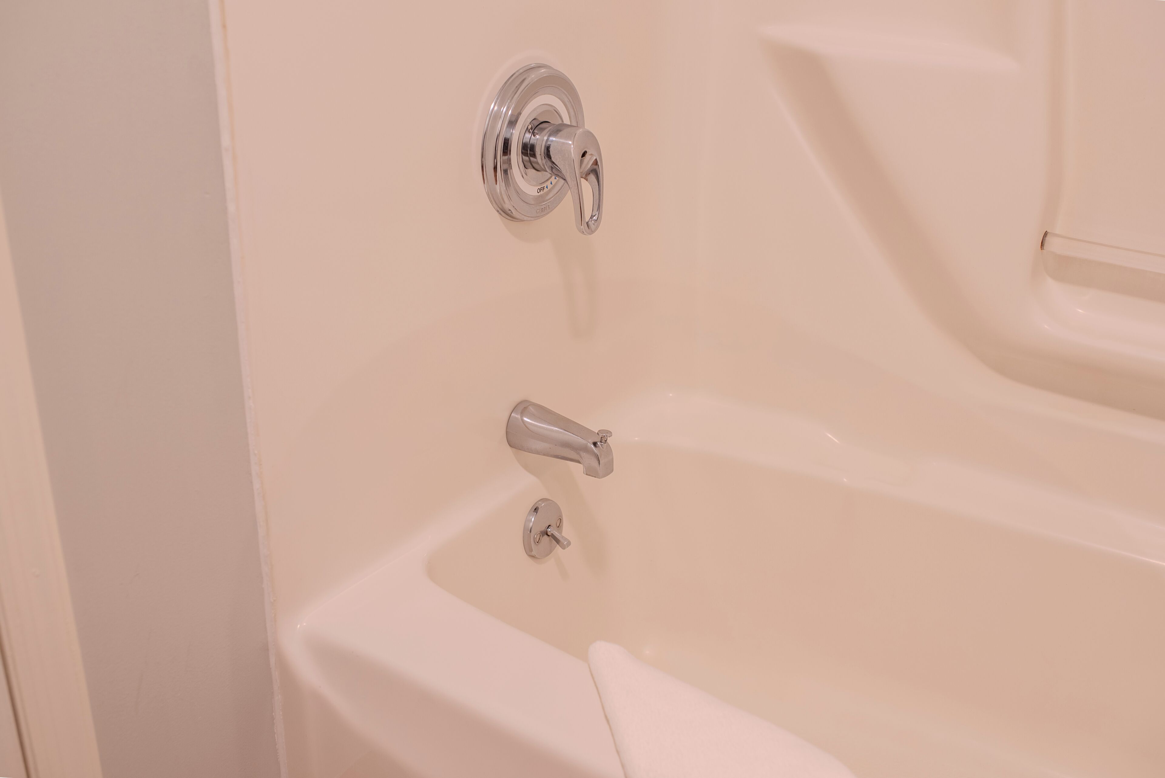 A bathtub with a faucet and a control knob.