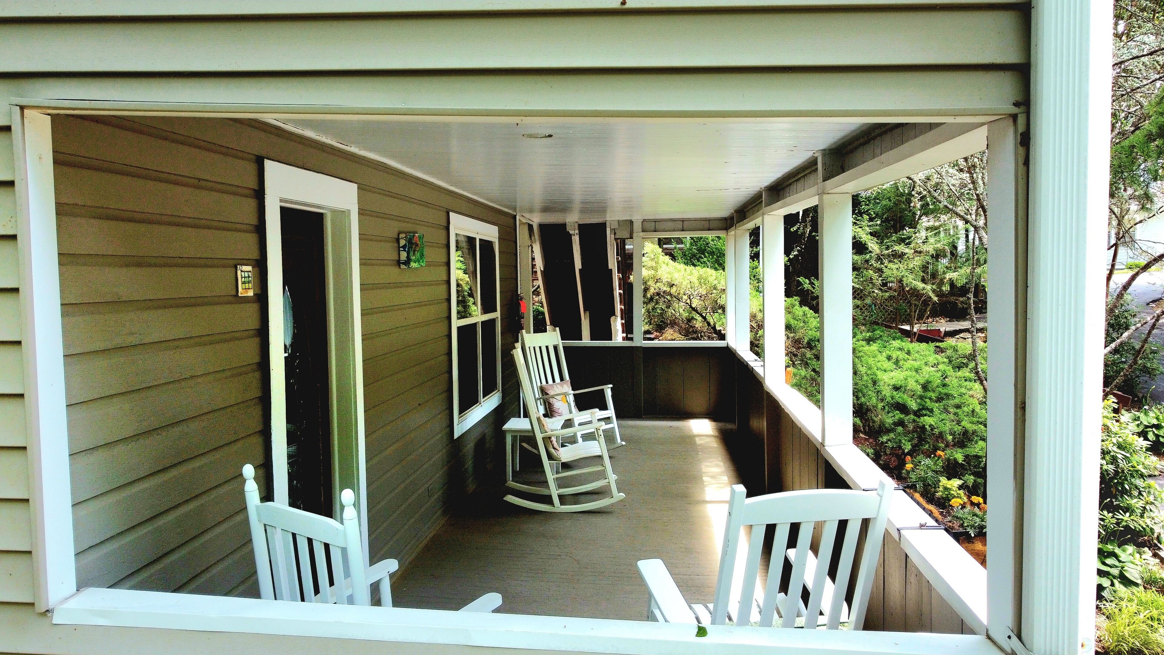 A covered porch with two rocking chairs and a small table.